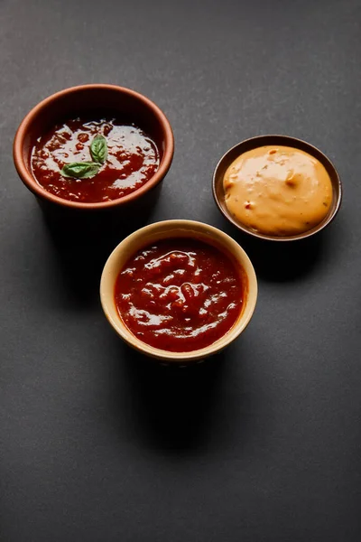 Bowls with red tomato and mustard sauces on black — Stock Photo