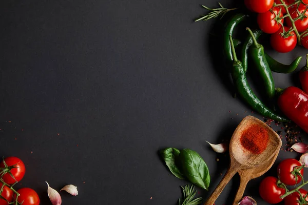 Vista superior de tomates cereja orgânicos, dentes de alho, alecrim fresco, pimenta, folhas de manjericão e pimentas verdes em preto — Fotografia de Stock