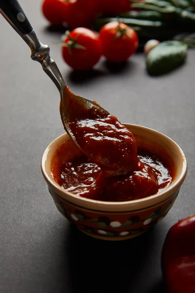 Selektiver Fokus des Löffels in Schüssel mit Tomatensauce auf schwarz — Stockfoto