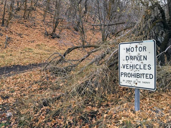 Motor Driven Vehicles Prohibited by order of the Sheriff sign with bullet holes, in forest trail on the Yellow Fork and Rose Canyon Trails in Oquirrh Mountains on the Wasatch Front in Salt Lake County Utah USA.