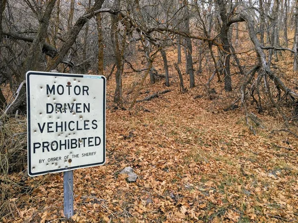 Motor Driven Vehicles Prohibited by order of the Sheriff sign with bullet holes, in forest trail on the Yellow Fork and Rose Canyon Trails in Oquirrh Mountains on the Wasatch Front in Salt Lake County Utah USA.