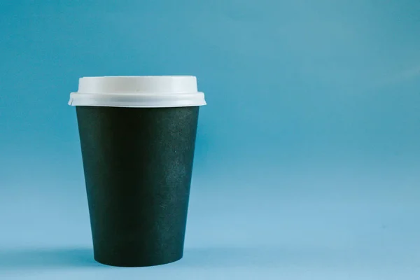 Tasse à café noire en carton avec couvercle sur fond bleu . — Photo