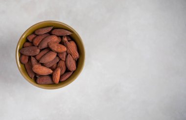 Yeşil bir kasede badem, arka planda desenli ışık, üst manzara. Boşluğu sağ tarafa kopyala.