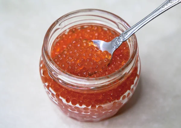 Memegang mangkuk kaca dengan kaviar merah. Sendok dalam kaviar merah. Makanan laut yang mahal, makanan lezat . — Stok Foto