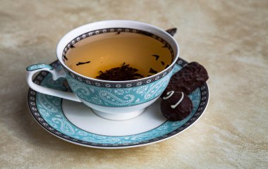 Bej desenli arkaplanda şekerli bir fincan siyah çay.