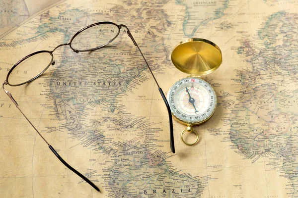 old gold compass with cover and spectacles on vintage map, macro