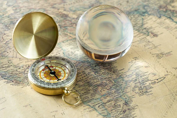 旧的黄金罗盘与封面和玻璃球在复古地图上, 宏观背景 — 图库照片