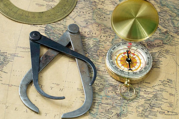 The old measuring tool gold compass with cover on vintage map, macro background, compasses Royalty Free Stock Images