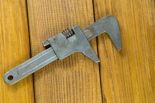 Las herramientas de mano - una pequeña llave ajustable viejo fondo de madera marrón — Foto de Stock