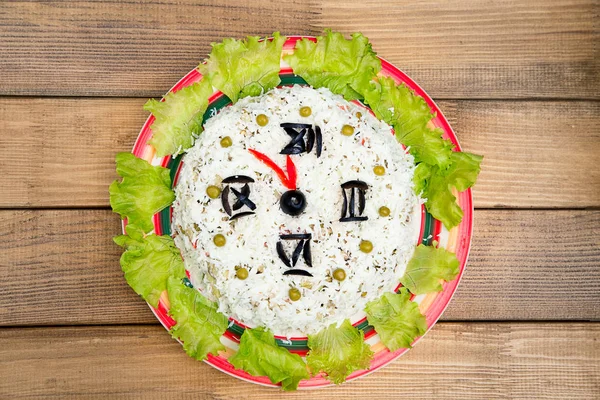 Noel salata pirinç zeytin yeşil bezelye - kavram yeni yıl saat yüzünü, gece yarısı, kahverengi ahşap zemin.