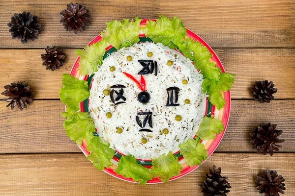 Noel salata pirinç zeytin yeşil bezelye - kavram yeni yıl saat yüzünü, gece yarısı, kahverengi ahşap zemin çam kozalakları masada.