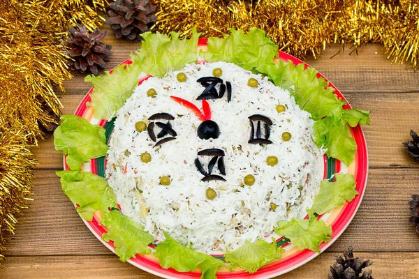 La ensalada navideña el arroz las aceitunas los guisantes - el concepto Nuevo año la esfera del reloj, la medianoche, el fondo castaño de madera los conos de abeto el oropel sobre la mesa . Fotos de stock libres de derechos