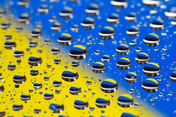 El fondo Abstracto azul-amarillo de las gotas de agua sobre el cristal con la reflectio, macro, el color de la bandera de concepto Ucrania en la foto la revolución de Maidán —  Fotos de Stock