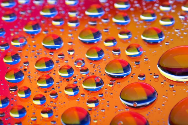 Abstraktní oranžové červené pozadí s přechodem barvy vody klesne na skle s odrazem, bockeh, makro — Stock fotografie