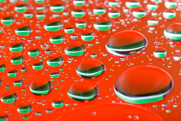 O fundo vermelho alaranjado abstrato com gotas de água da cor do gradiente no vidro com reflexão, gota grande, macro — Fotografia de Stock