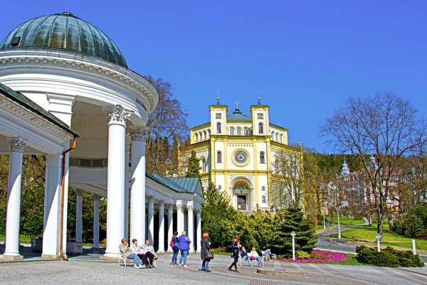 Columnata de primavera Karolina e iglesia católica en la pequeña ciudad balneario de Bohemia Occidental Marianske Lazne (Marienbad) - República Checa — Foto de Stock