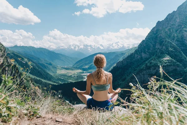 Fiatal lány meditál, a háttérben a hegyek — Stock Fotó