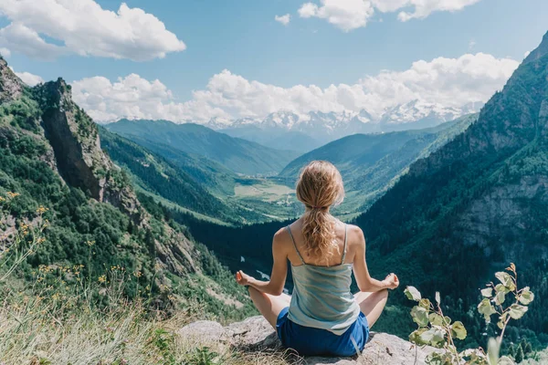 Fiatal lány meditál, a háttérben a hegyek — Stock Fotó