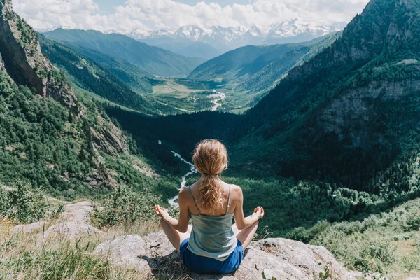 Fiatal lány meditál, a háttérben a hegyek — Stock Fotó