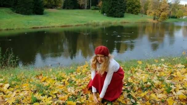 Šťastná dívka hází na podzim listy v parku v pomalém pohybu — Stock video