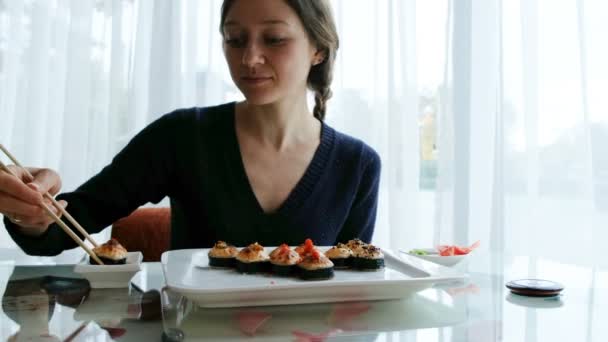Joven chica caucásica comiendo sushi en un restaurante japonés — Vídeo de stock