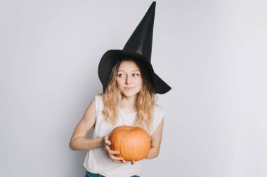 bir beyaz t-shirt kabak ile siyah şapka Cadılar Bayramı için beyaz arka plan üzerinde poz içinde genç güzel beyaz kız