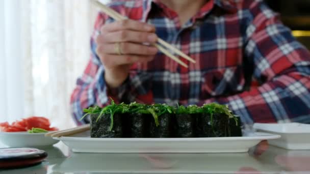 Joven comiendo sushi en un restaurante japonés — Vídeos de Stock