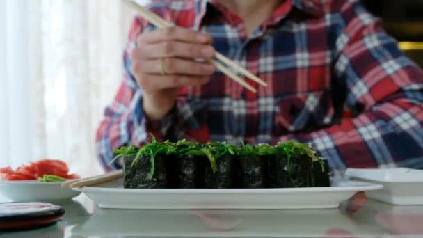 Jovem comendo sushi em um restaurante japonês — Vídeo de Stock