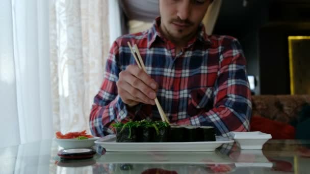 Joven comiendo sushi en un restaurante japonés — Vídeos de Stock