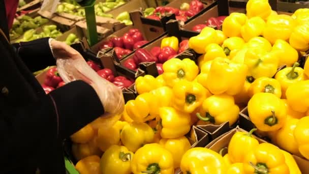 Młoda dziewczyna w supermarkecie wybiera soczystej, świeżej żółtej papryki i umieszcza go w pakiecie zbliżenie. — Wideo stockowe