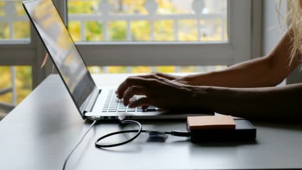 Mädchenhände arbeiten mit Laptop am Fenster — Stockvideo