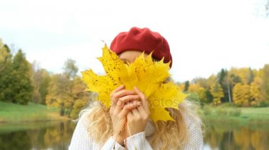 Akçaağaç yapraklarıyla sonbahar parkında poz veren çekici beyaz kadın.