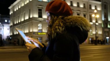 Ekran ve parmak ucu ve gülümsüyor arıyor tablet ile genç kız. Arabalar hareket ve insanların kalabalıklar yürüme gece city, arka plan üzerinde