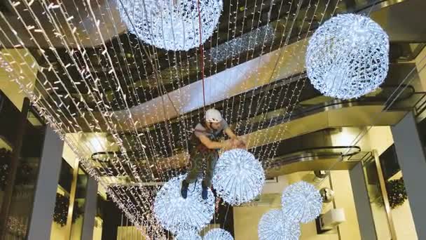 Alpinista industrial monta decorações de Natal no espaço não suportado no centro comercial — Vídeo de Stock