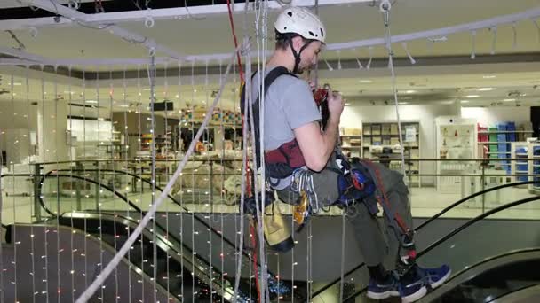 Alpinista industrial monta decorações de Natal no espaço não suportado no centro comercial — Vídeo de Stock