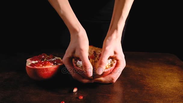 Ženské ruce přestávka půl granátové jablko v polovině na hnědý stůl a tmavým pozadím, detailní zpomalené v rozlišení 4k. — Stock video