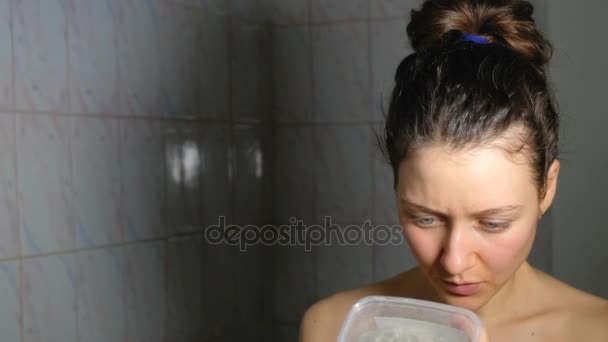 Молодая девушка внимательно изучает инструкции по нанесению маски для лица в ванной комнате, 4K . — стоковое видео
