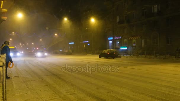 Menschen überqueren an einem Winterabend im Schnee die Straße an einem Fußgängerüberweg 4k. — Stockvideo