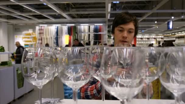 A young man chooses a product in the supermarket, looking glasses, 4K. — Stock Video