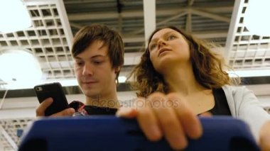 Süpermarkette alışveriş yaparken genç bir çift bir adam telefon, 4 k görünüyor..