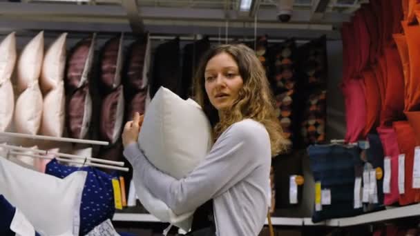Chica joven elige una almohada en el centro comercial, 4K . — Vídeos de Stock