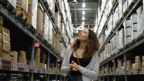 Ung tjej söker varor på ett lagerställe shoppingcenter, 4k. — Stockvideo