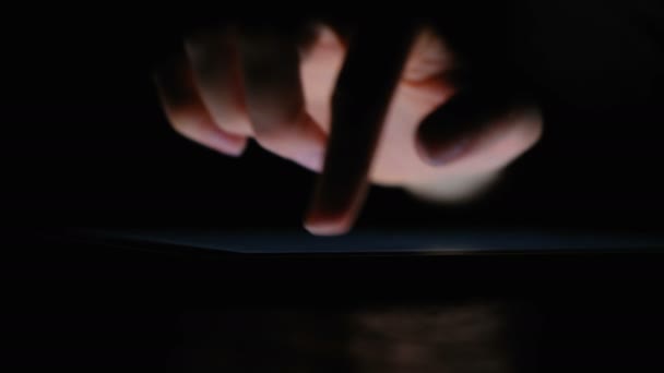 La mano escribe en la tableta con el dedo en la oscuridad de cerca, 4k . — Vídeo de stock