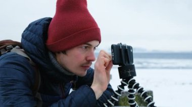 Gülümseyen adam telefon bir tripod üzerinde görünüyor ve kışın, 4 k ekran dokunur.
