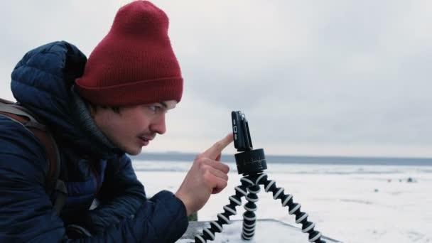 El hombre mira el teléfono en un trípode y toca la pantalla en invierno, 4K . — Vídeo de stock