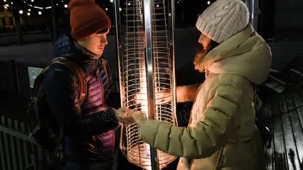 Un couple aimant se réchauffe les mains en plein air, 4K . — Video