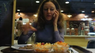 Kız bir kafede yemek yiyor ve telefonda konuşurken, 4 k pencereden görüntüleme.