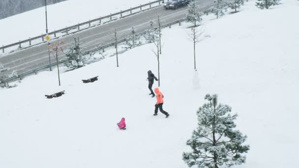 Jong gezin met een kind spelen sneeuwballen in de buurt van de weg, 4k. — Stockvideo