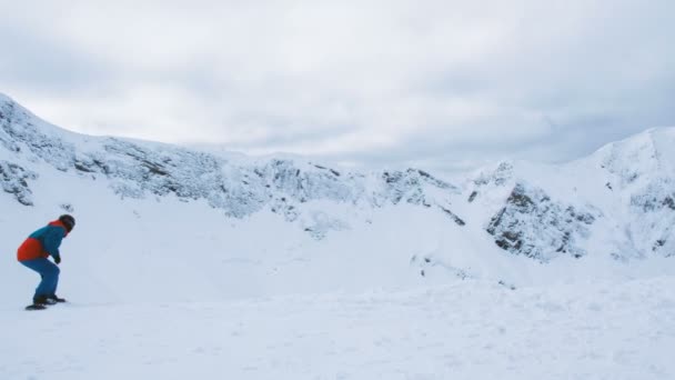 Turyści pochodzą na desce snowboardowej w tle śniegiem gór w ośrodku narciarskim, 4k. — Wideo stockowe