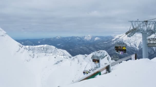 Los telesillas de cuatro plazas abiertas en las montañas llevan a los esquiadores y snowboarders al lugar donde comienza el descenso, 4k . — Vídeos de Stock